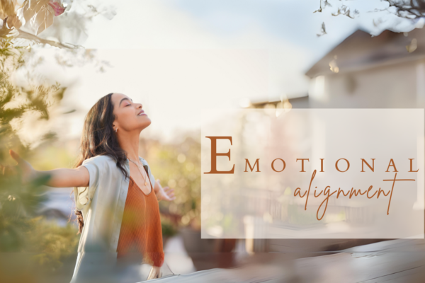 A woman embracing the warmth of the sun with open arms in a serene outdoor setting, symbolizing spiritual alignment and inner peace with text emotional alignment.